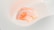 A human brain model is floating against a soft, abstract white background with curved, ribbed structures. The brain is illuminated with a warm, glowing hue, highlighting its intricate surface details.