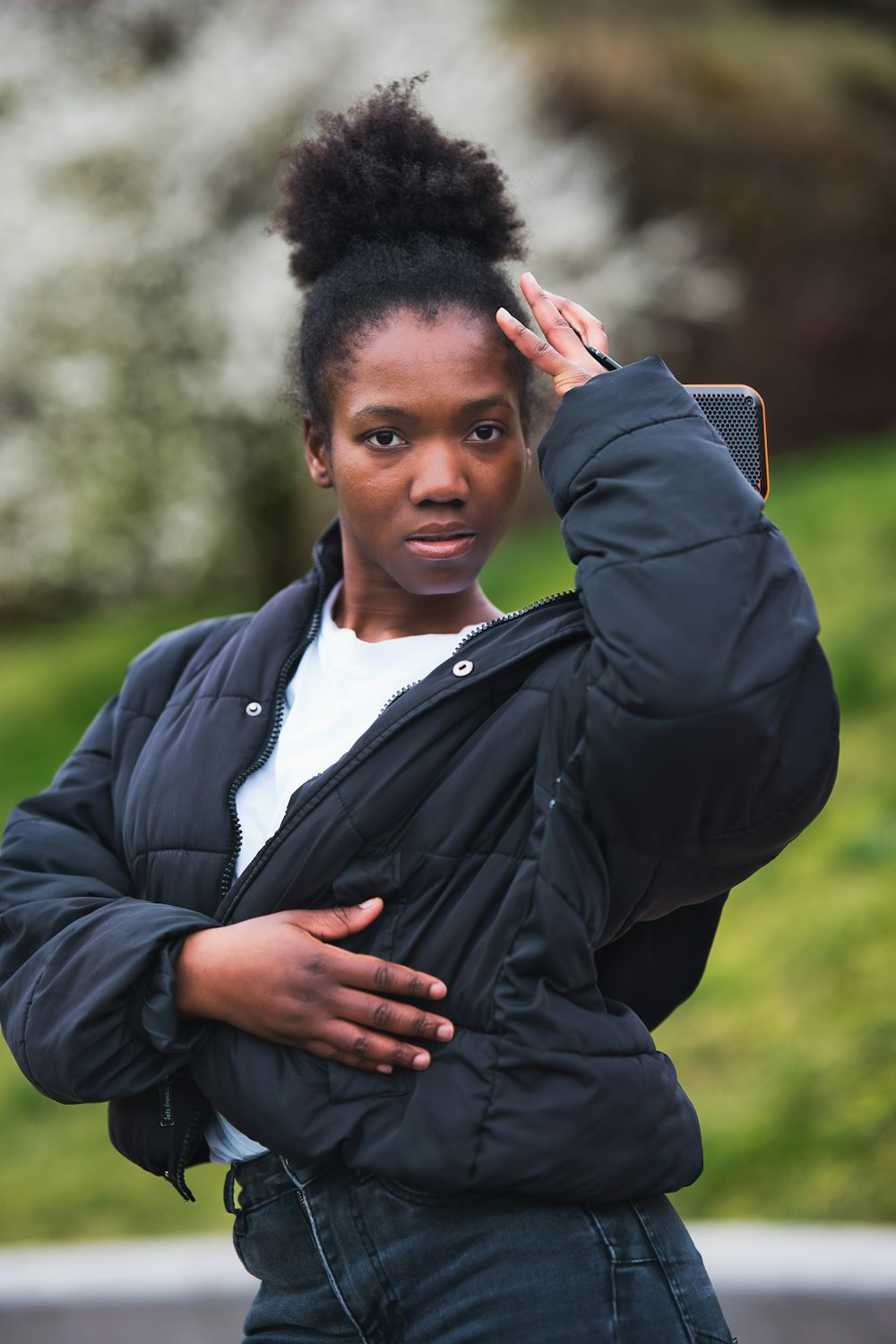 a woman with a black jacket is holding her hand on her head