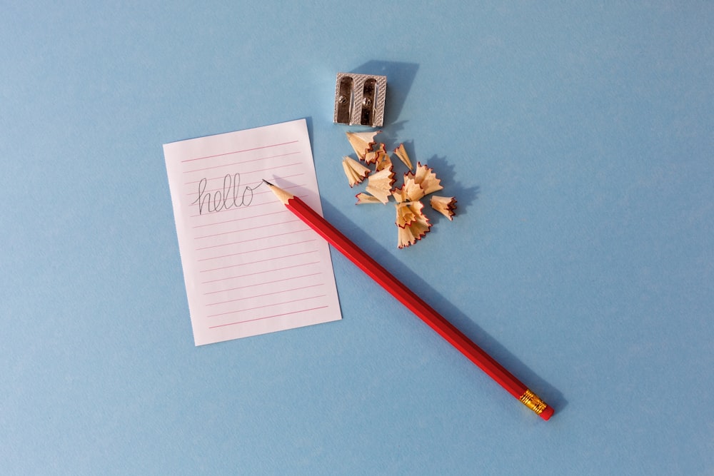 um bloco de notas, lápis e apontador de lápis em uma superfície azul