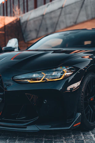 Close-up of a sleek front splitter on a black Ford Mustang in an urban night setting.