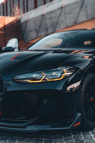 Close-up of a sleek front splitter on a black Ford Mustang in an urban night setting.