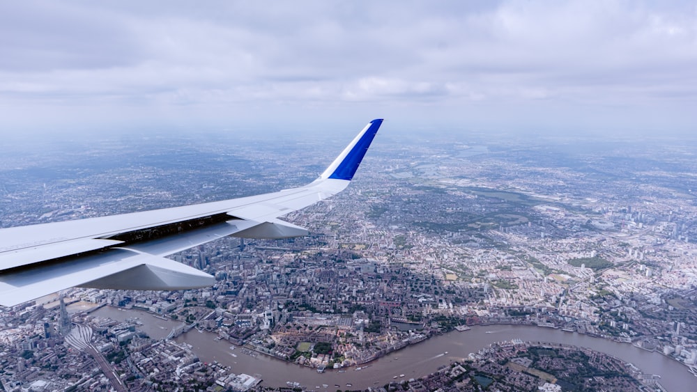 an airplane wing flying over a city and a river