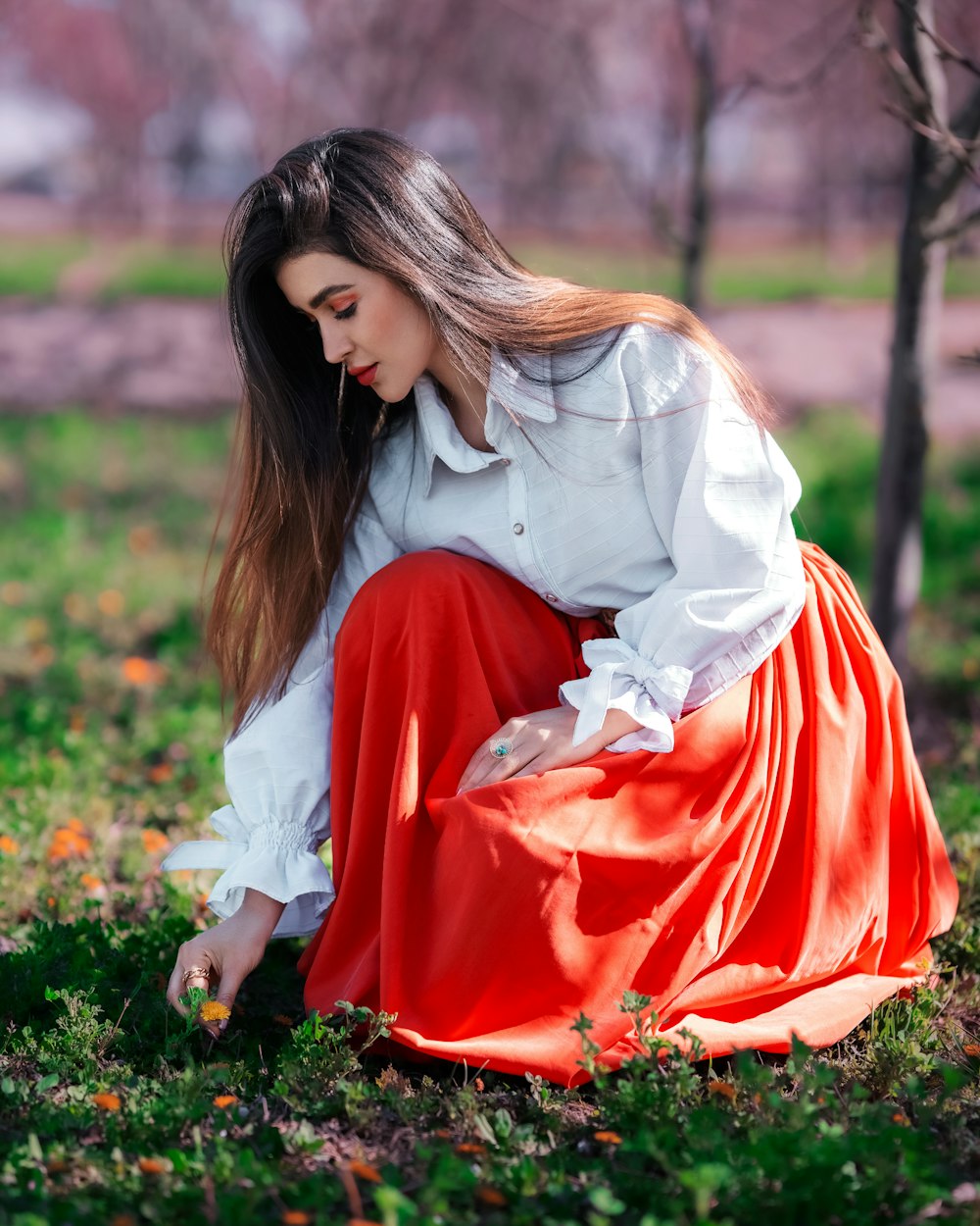 a woman kneeling down in a field of grass