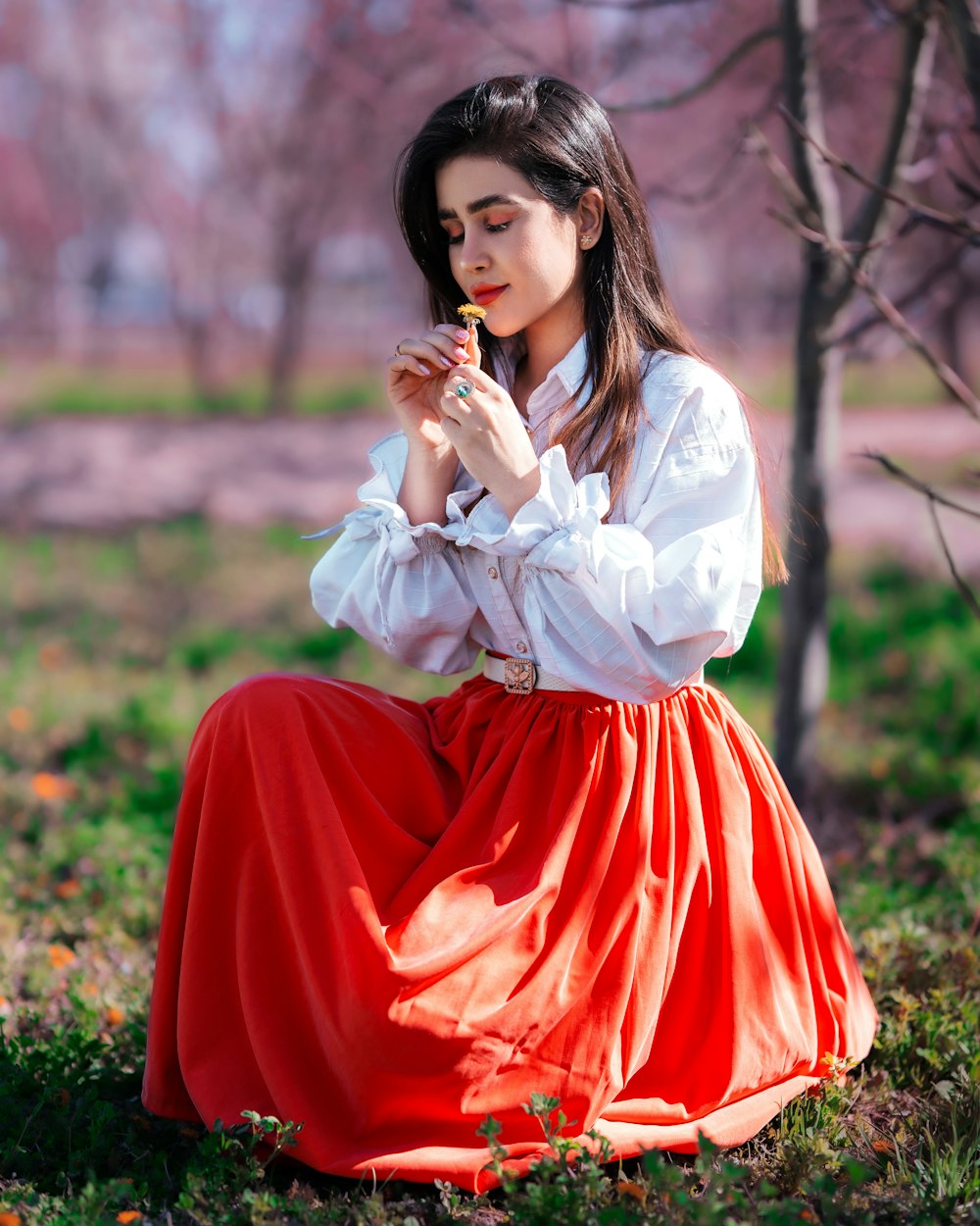 a woman in a long red skirt sitting on the ground