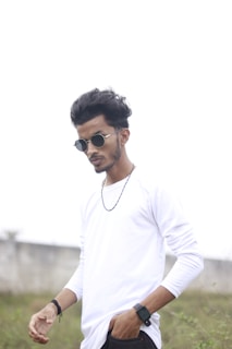Man wearing a casual outfit accessorized with a sleek watch and sunglasses outdoors.