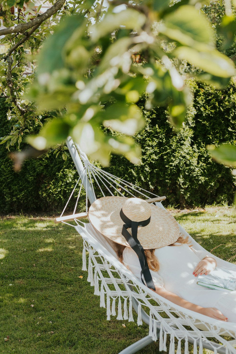 a woman laying in a hammock with a hat on her head