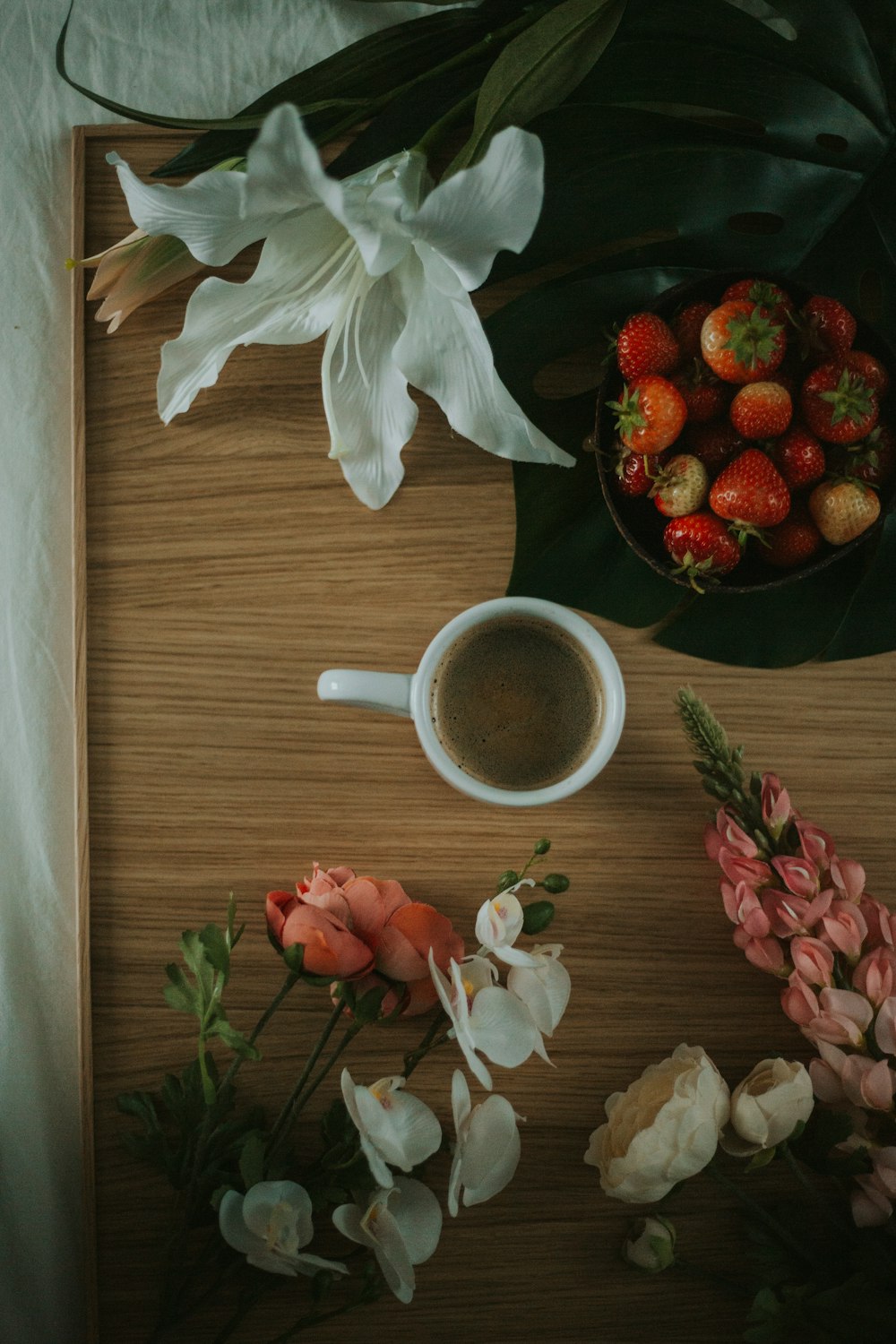a wooden table topped with flowers and a cup of coffee