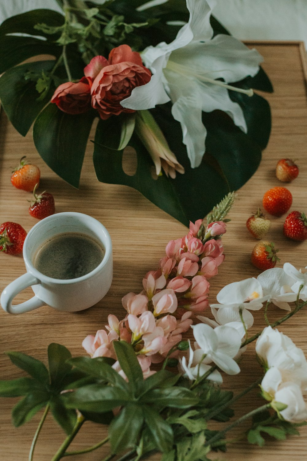 a cup of coffee and some flowers on a table