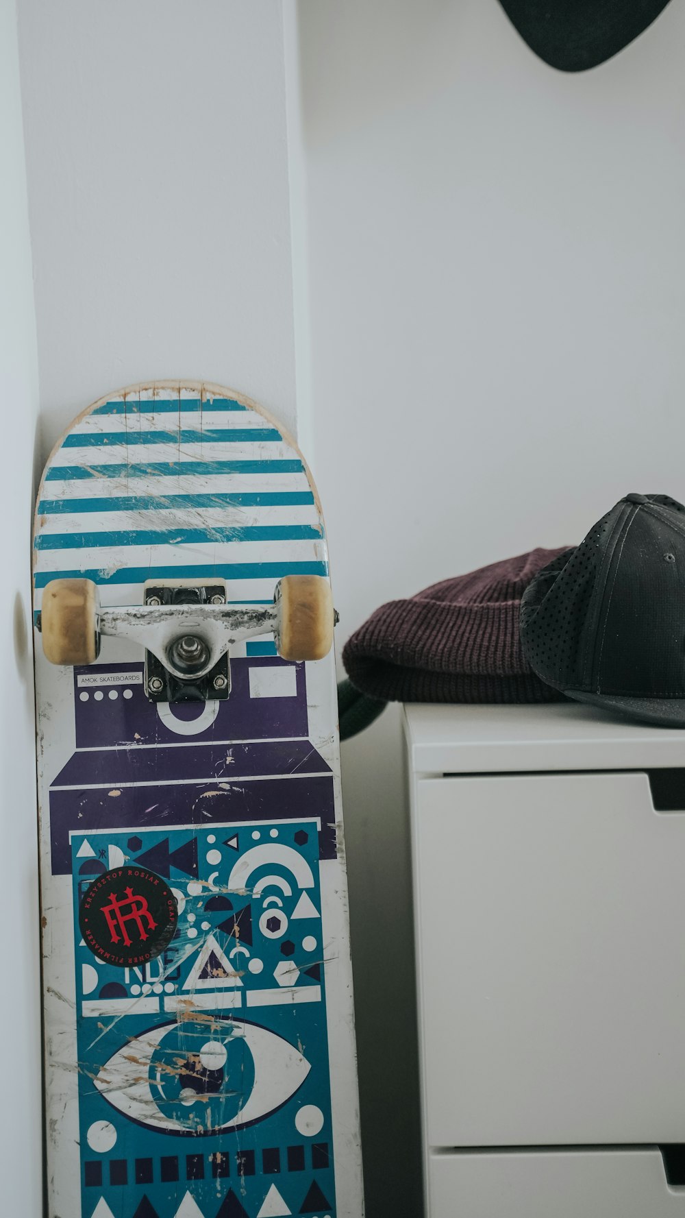 a skateboard sitting on top of a dresser next to a hat
