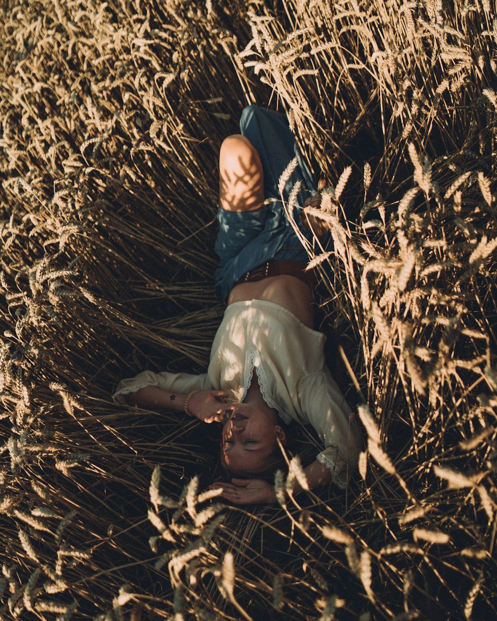 a woman laying on her back in a field of tall grass