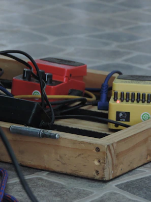 A row of handcrafted guitar pedals lined up on a rustic wooden table.