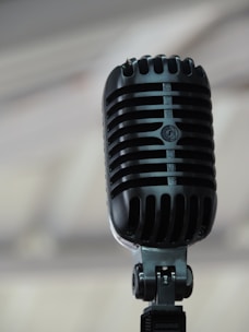A vintage microphone with soft cream and black tones, set against a minimalist backdrop.