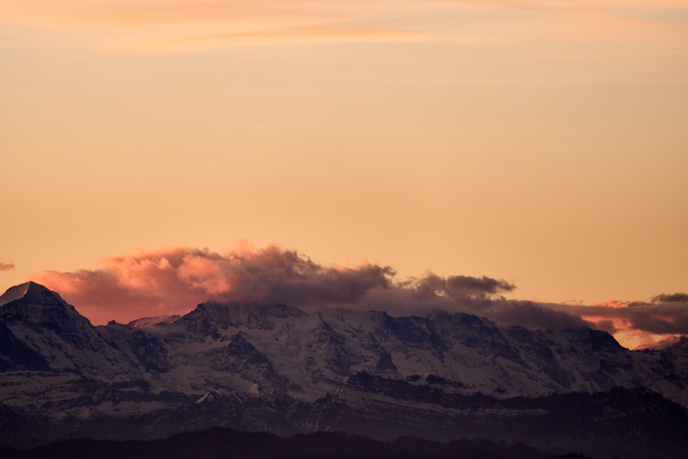 a plane flying in the sky with a mountain in the background