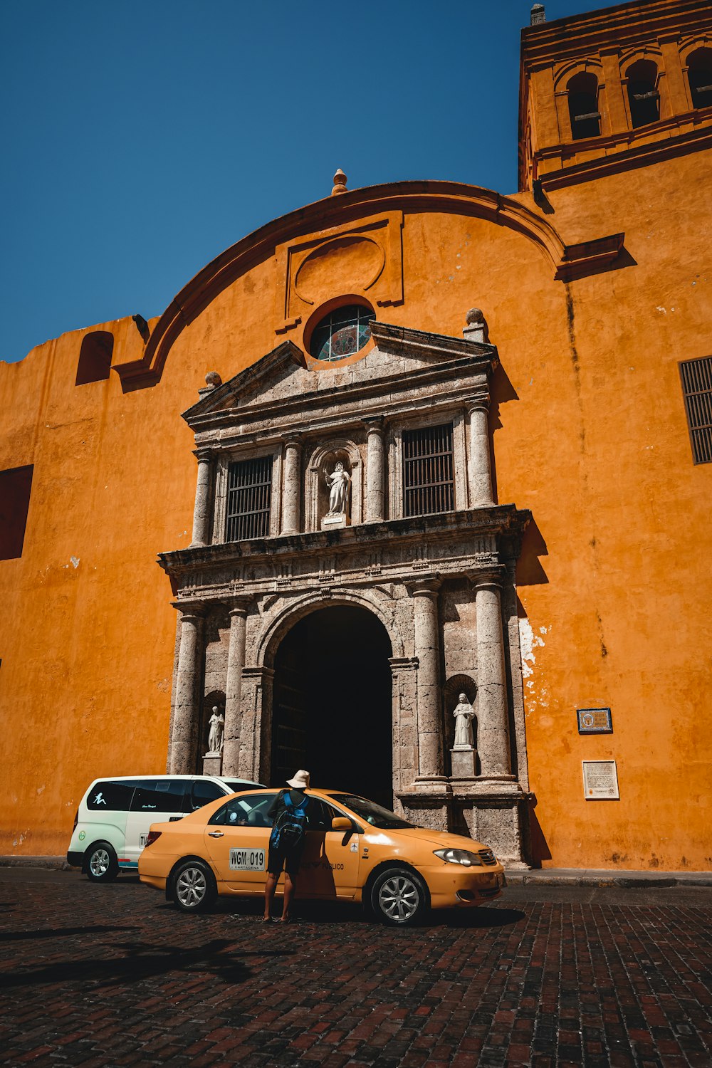 a yellow car parked in front of a tall building