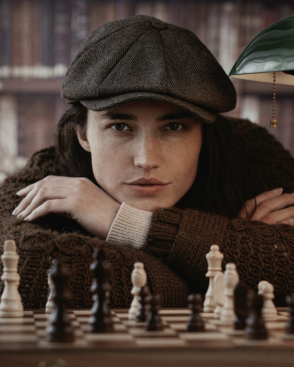 Una mujer apoyada en un tablero de ajedrez con un sombrero en la cabeza