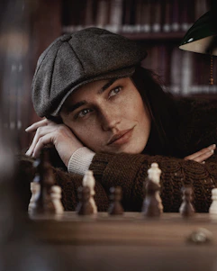 A thoughtful young person concentrating deeply over a chessboard in a warm, inviting study room.