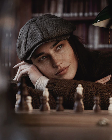 A thoughtful young person concentrating deeply over a chessboard in a warm, inviting study room.