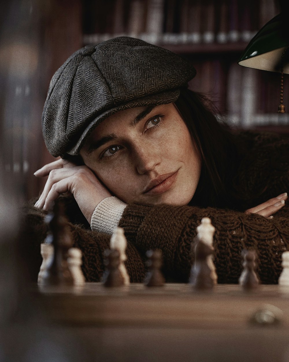 a woman leaning her head on a chess board