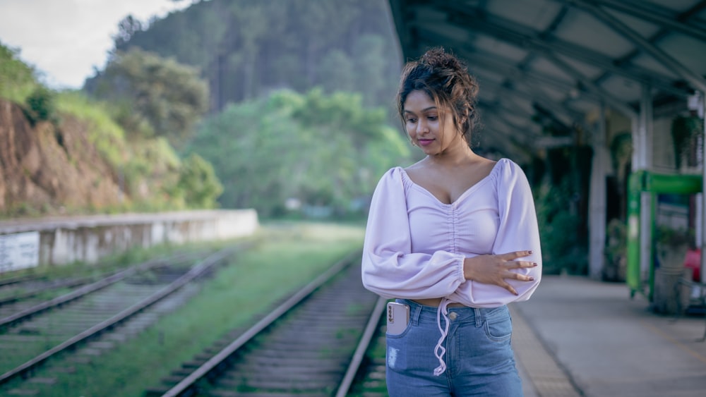 a woman standing on a train track next to a train station