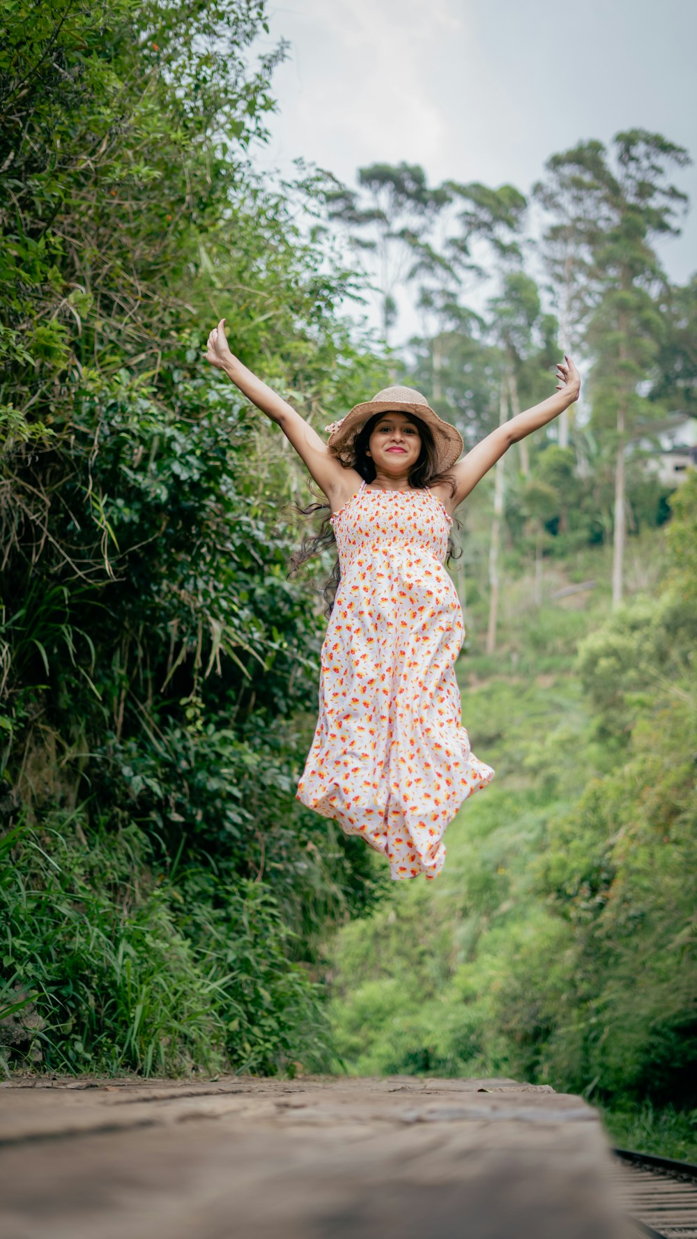 a woman in a dress and hat jumping in the air