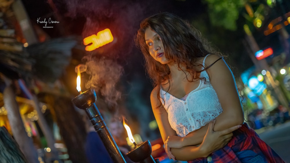 a woman standing next to a pole with a lit candle