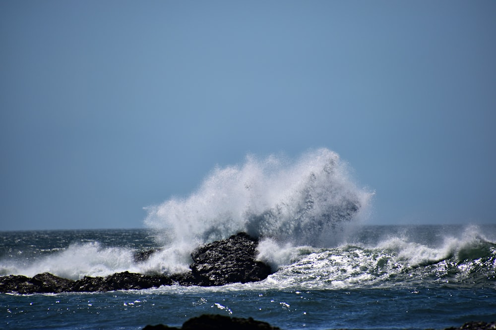 a large wave crashing over a rock in the ocean