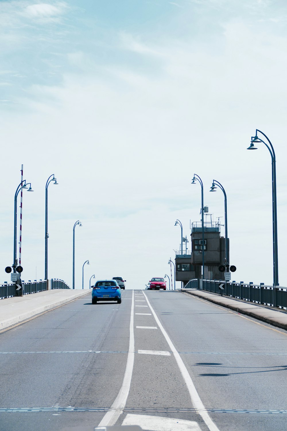 a blue car driving across a bridge over water