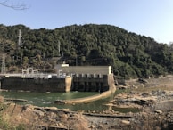 Aerial shot of a hydroelectric facility nestled in a mountainous forest area.