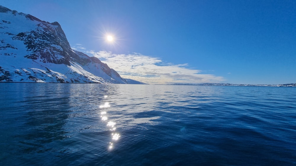 the sun shines brightly over the water of a mountain lake