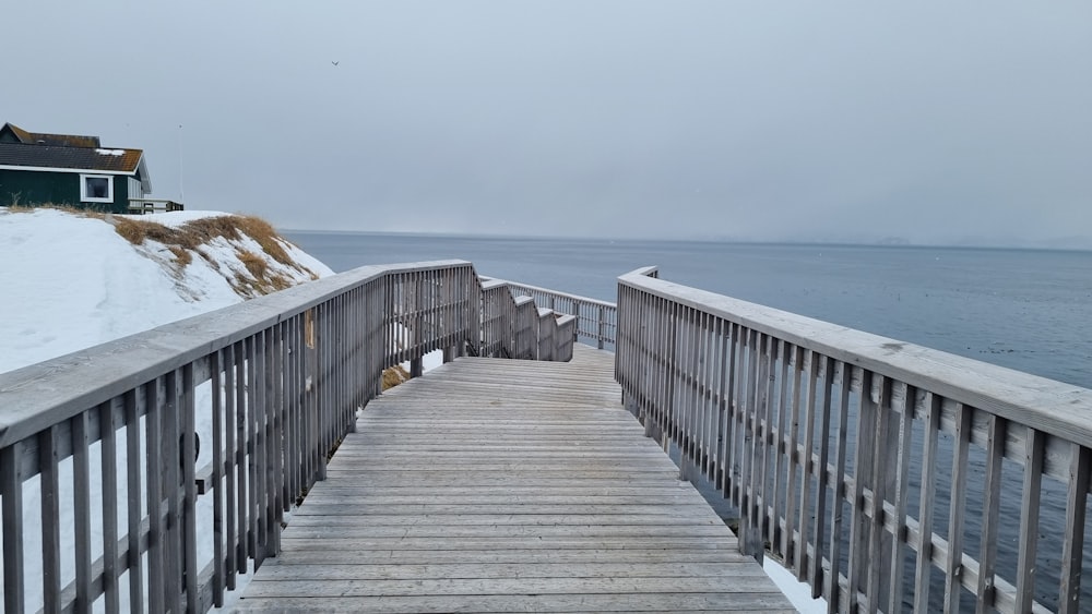 a wooden walkway leading to a house on a snowy day