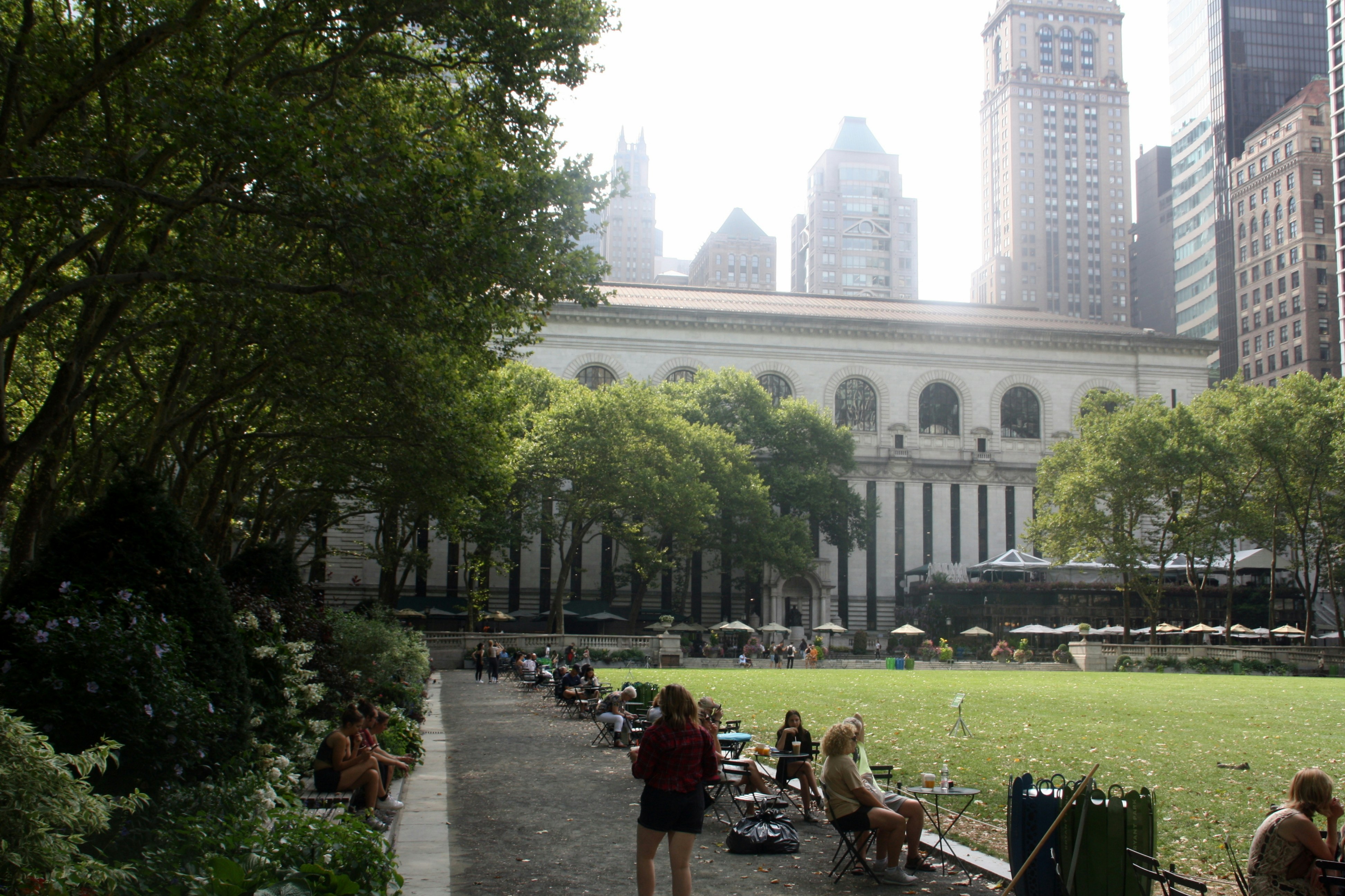 Visitors relaxing on benches in Bryant Park with Midtown high-rises rising behind them