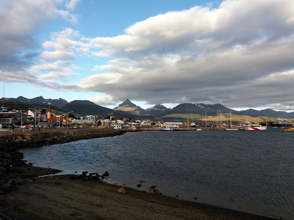 a body of water surrounded by mountains under a cloudy sky