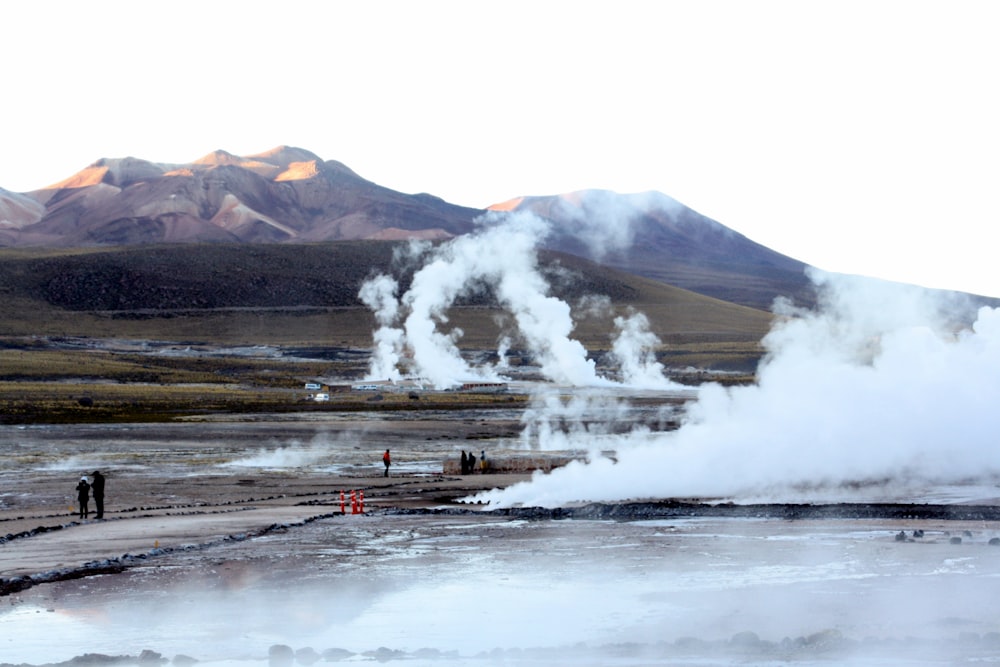 a group of people standing in front of a geyser