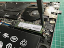 Technician repairing a laptop motherboard with precision tools.