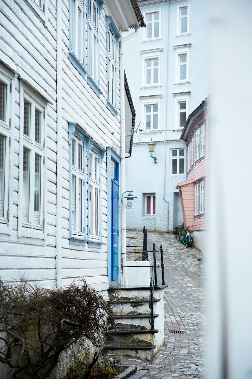 a cobblestone street lined with white wooden buildings