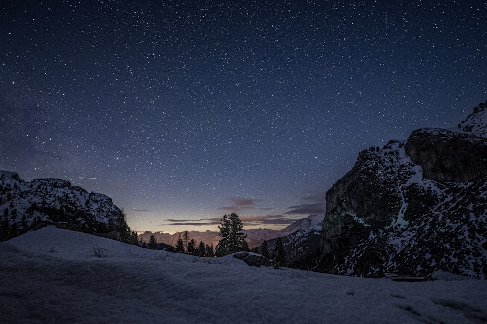 a night sky with stars above a snowy mountain