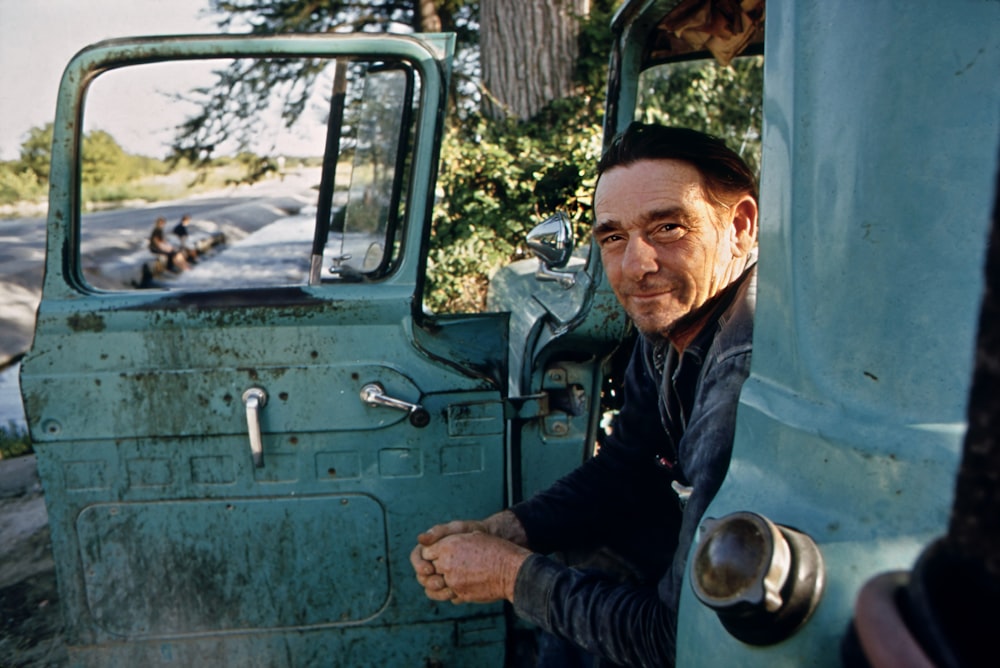 a man leaning out the door of a green truck