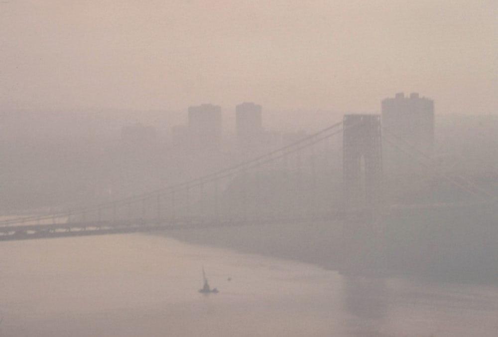 a foggy view of a bridge over a body of water