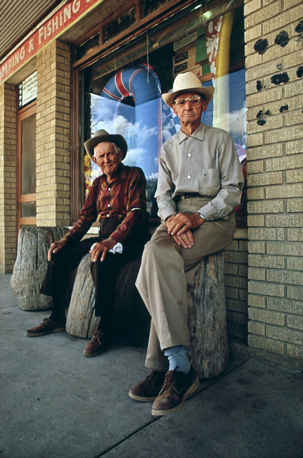 a man and a woman sitting on a bench in front of a building