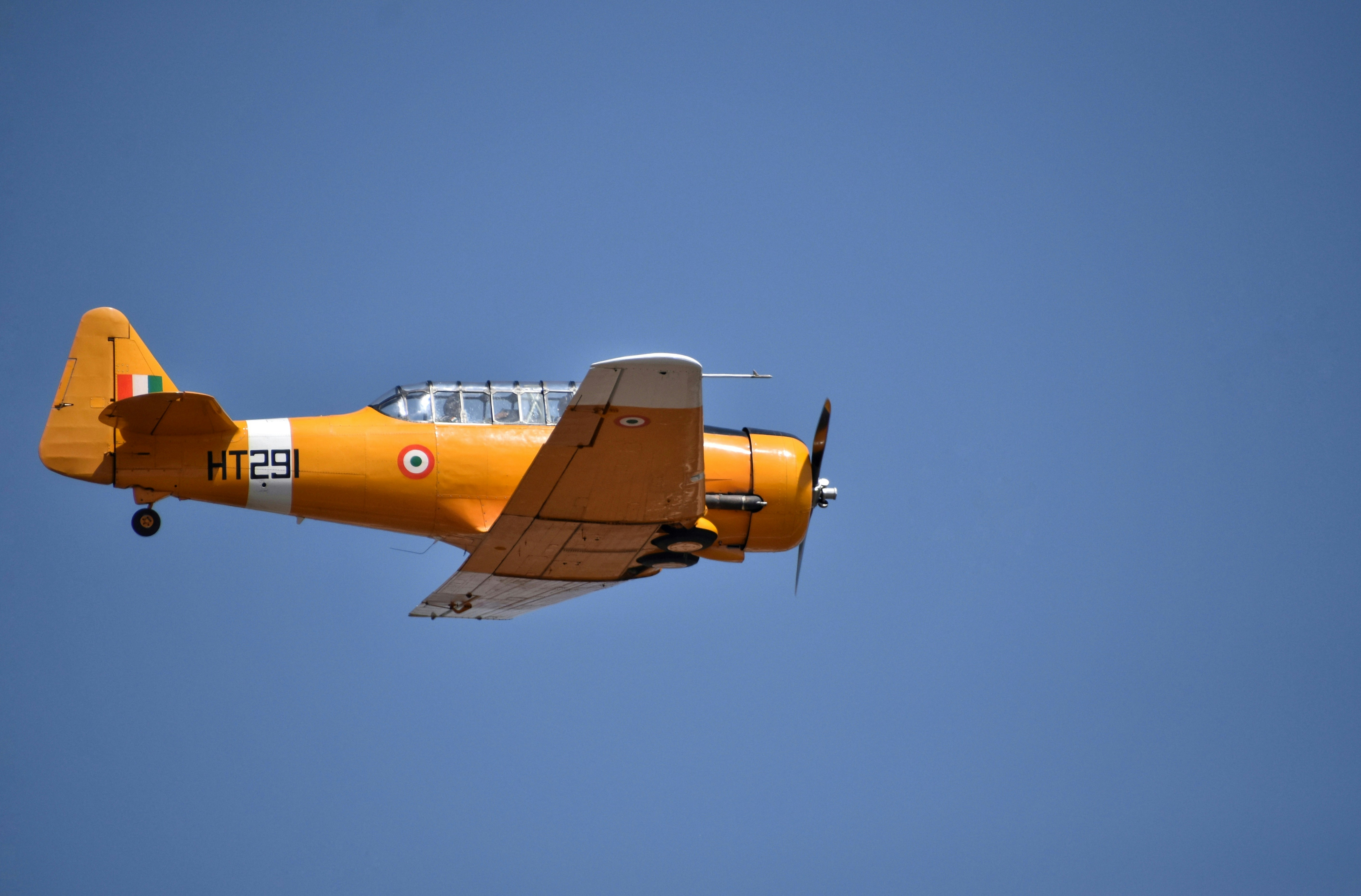 a small yellow airplane flying through a blue sky