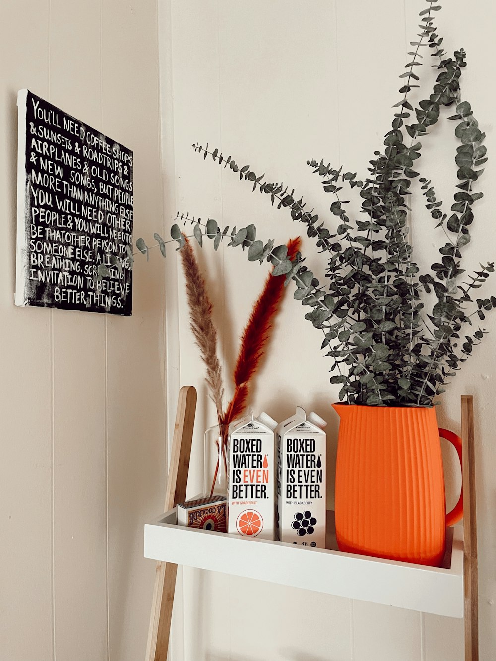 a shelf with a vase of plants and a couple of boxes of milk