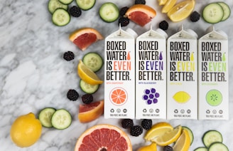 three boxes of boxed water are surrounded by sliced fruit