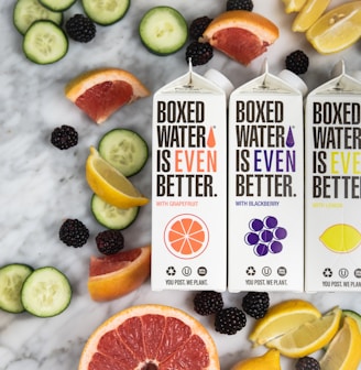 three boxes of boxed water are surrounded by sliced fruit