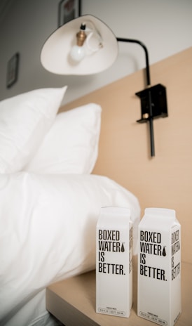 two boxes of boxed water sitting on a bed