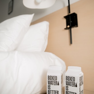 two boxes of boxed water sitting on a bed