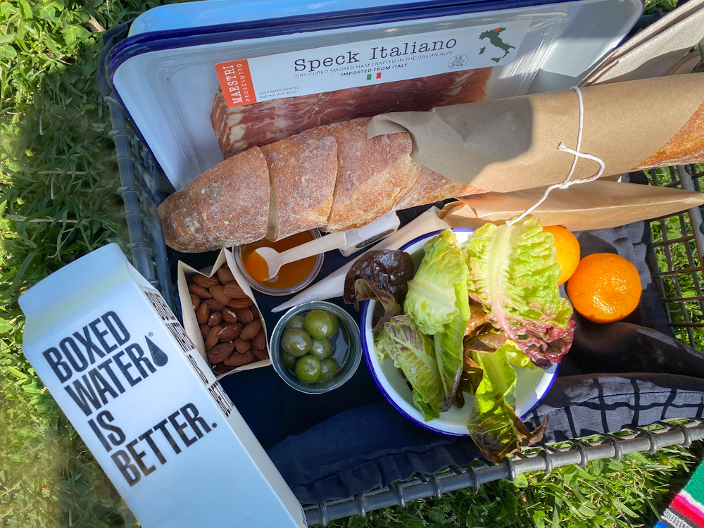 a variety of food is laid out on a picnic blanket