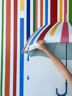 a person holding an umbrella in front of a colorful wall