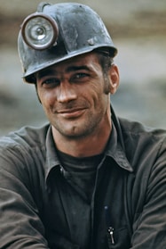 A miner wearing protective gear inspecting mining equipment outdoors.