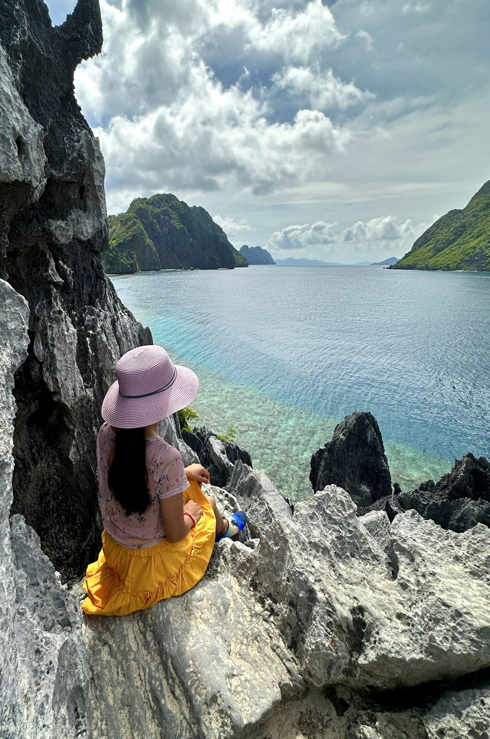 a woman sitting on top of a rock next to a body of water