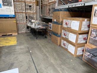 Stacks of assorted customer return boxes from Walmart and Amazon ready for resale in a bright warehouse setting.